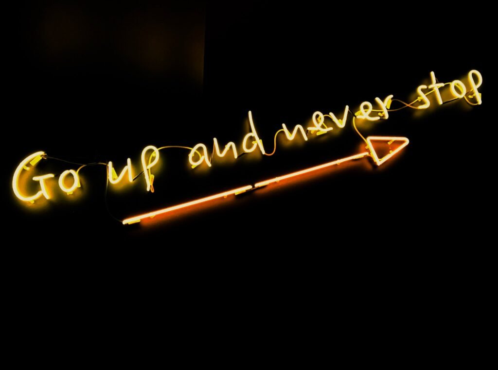 A lit up pencil with words " go up and never stop ".
